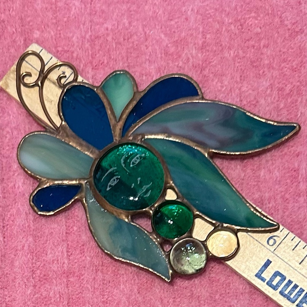 Stained glass window decoration. Has etched face on green center stone.